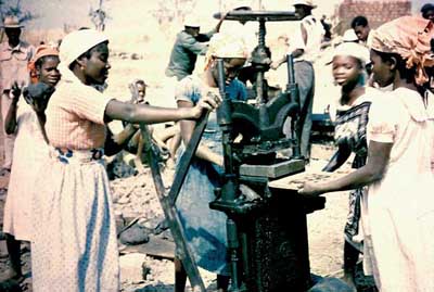 These women are working to make floor tiles set in cement. Belina, left, is a trained health worker.